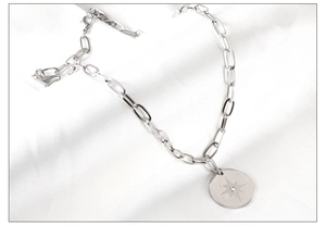 Detail of silver paperclip chain necklace featuring an oval starburst pendant with crystal
