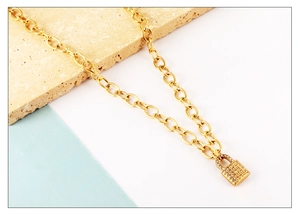 Macro shot of gold chunky link chain necklace featuring a pavé diamond padlock pendant