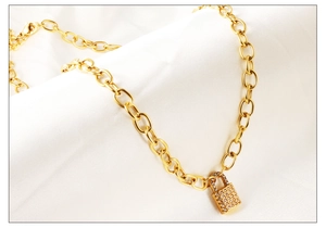 Macro detail of gold lock pendant necklace with sparkling crystals on white silk