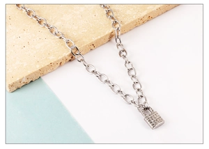 Macro detail of silver link chain with crystal-encrusted padlock pendant on stone