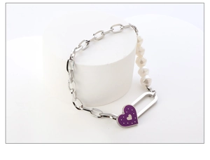 Details des silbernen Armbands mit Perlen und einem violetten Emaille-Herzanhänger