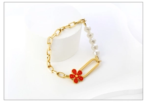 Detail eines Vintage-Goldkettenarmbands mit weißen Perlen und rotem Blumenanhänger