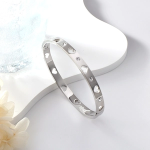 Polished silver stainless steel bangle featuring hollow heart patterns and crystals