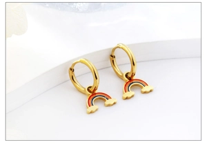 Macro shot of gold stainless steel hoop earrings with colorful rainbow charms on white blocks