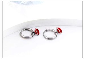 Macro view of silver stainless steel hoop earrings with red lip enamel charm pendants
