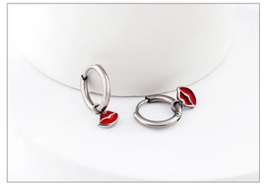 Detail of silver hoop earrings featuring glossy red enamel lip charms on white stand