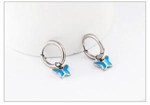 Detail of silver hoop earrings featuring blue butterfly pendants with black outlines