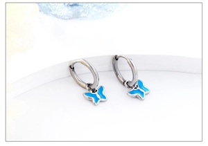 Detailed close-up of butterfly hoop earrings featuring blue enamel and silver finish