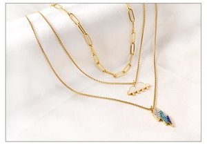 Detailed close-up of layered gold necklaces with white cloud and blue rhinestone lightning bolt