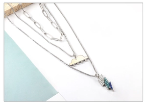 Close-up of triple-layered silver necklace with cloud pendant and blue gradient lightning