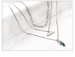 Close-up of triple-layered silver necklace with paperclip chain and enamel cloud pendant