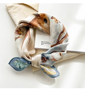 Close-up of silk square scarf with deer and floral prints on elegant white fabric