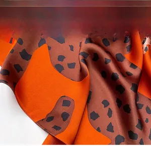 Close-up of fine overlock stitching on vibrant orange and brown leopard silk scarf