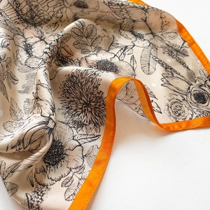 Detailed close-up of vintage floral silk scarf with vibrant orange hand-rolled edges
