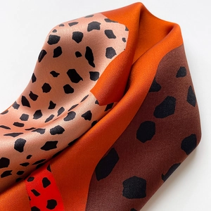 Macro shot of silk scarf showing leopard print patterns and soft satin fabric texture