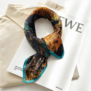 Detailed view of printed silk scarf with floral patterns on beige shirt and magazine