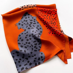 Macro detail of silk square scarf featuring orange and gray leopard print patterns