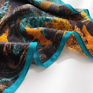 Detailed close-up of premium silk scarf featuring abstract bird print and blue satin edges