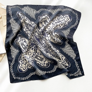 Detailed view of dark blue and white silk scarf with baroque floral patterns on texture