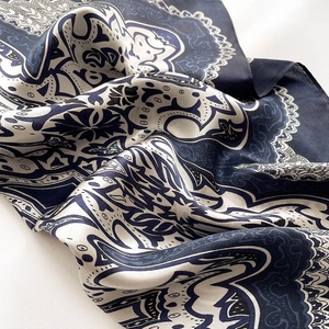 Detailed close-up of premium silk scarf with navy blue and ivory floral patterns