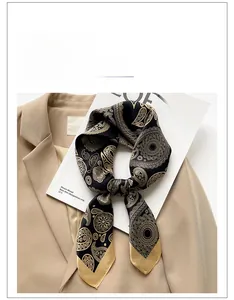 Close-up of black and gold paisley silk scarf tied in a bow on a beige blazer