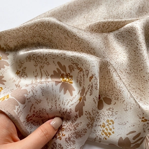 Macro shot of champagne floral silk scarf showing soft satin texture and elegant drape