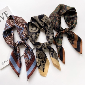 Three elegant paisley silk scarves in blue, gold, and green with luxurious silk texture