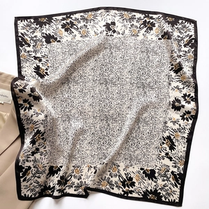 Elegant floral silk square scarf with black borders, styled with a beige blazer