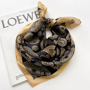 Elegant black and gold paisley silk scarf with premium satin finish on magazine background