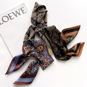 Detailed view of three silk scarves with paisley patterns in black, green and blue tones