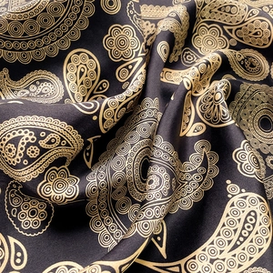 Macro shot of silk scarf fabric showing golden paisley pattern and luxurious black texture