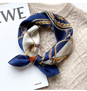 Close-up of navy blue silk scarf with golden chain pattern on a cozy sweater