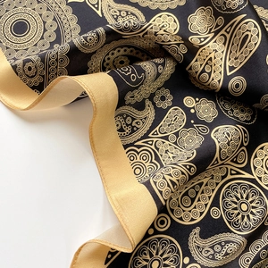 Close-up of luxury black and gold paisley silk scarf with detailed mandala patterns