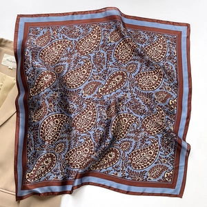 Detail of silk paisley square scarf styled with a beige blazer for an elegant office look