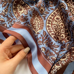 Detailed macro view showing the silky texture and paisley pattern of the silk scarf