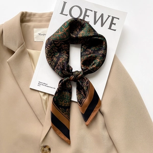 Elegant paisley silk scarf in green and brown styled on a beige blazer jacket
