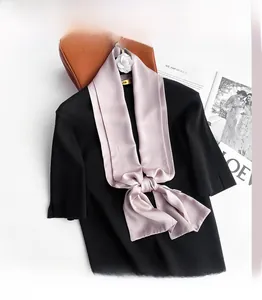 Close-up of a premium light pink silk scarf styled on a black knit sweater with luxury decor