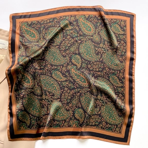 Close-up of square silk scarf with paisley patterns laid next to a khaki blazer