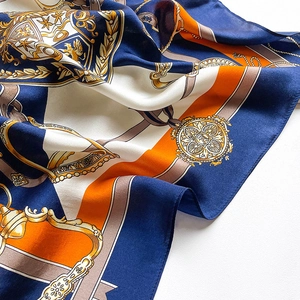 Close-up of silk scarf with equestrian chain patterns and vibrant orange accents