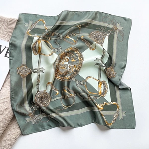 Detail of silk scarf with equestrian chain pattern on beige knit sweater background