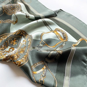 Detail of silk scarf with green stitching and gold equestrian horsebit pattern