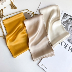 Detailed view of silk-feel scarves in ginger, champagne, and cream with soft sheen