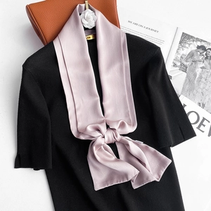Close-up of light purple silk scarf tied in a bow on a black knit top with stylish decor