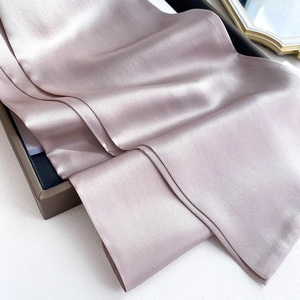 Detailed view of champagne pink silk scarf with soft pearl luster and smooth texture