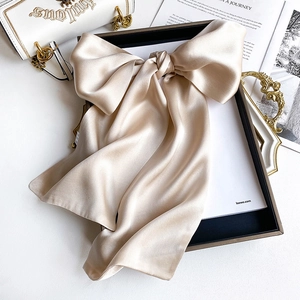 Detail of elegant champagne gold silk scarf styled as a bow on a luxury tray background