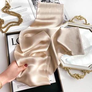 Detailed shot of luxurious champagne silk scarf showing soft drapes and smooth texture