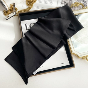 Close-up of black silk scarf texture with professional wash label in a luxury gift box