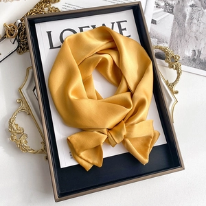 Detail of golden silk satin scarf tied in a bow on luxury background styling