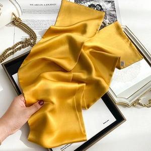 Detail view of mustard yellow silk scarf with elegant satin finish and smooth texture