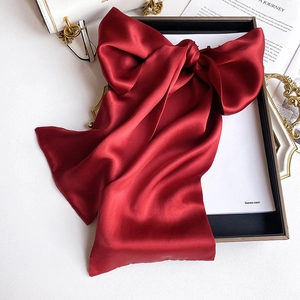 Detail shot of a dark red silk satin bow accessory with soft pearlescent luster and texture